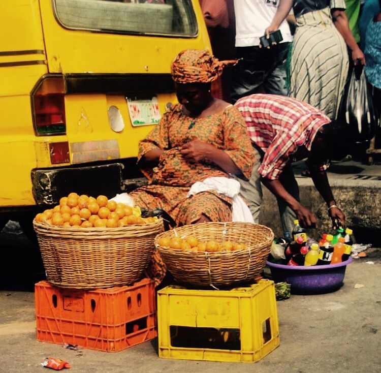 Baskets of oranges for sale beside a parked vehicle